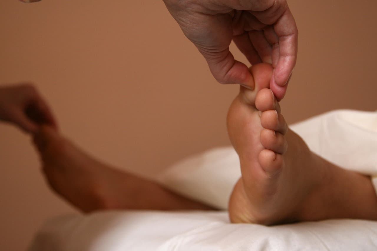 A foot being massaged during a pedicure, on a white pillow